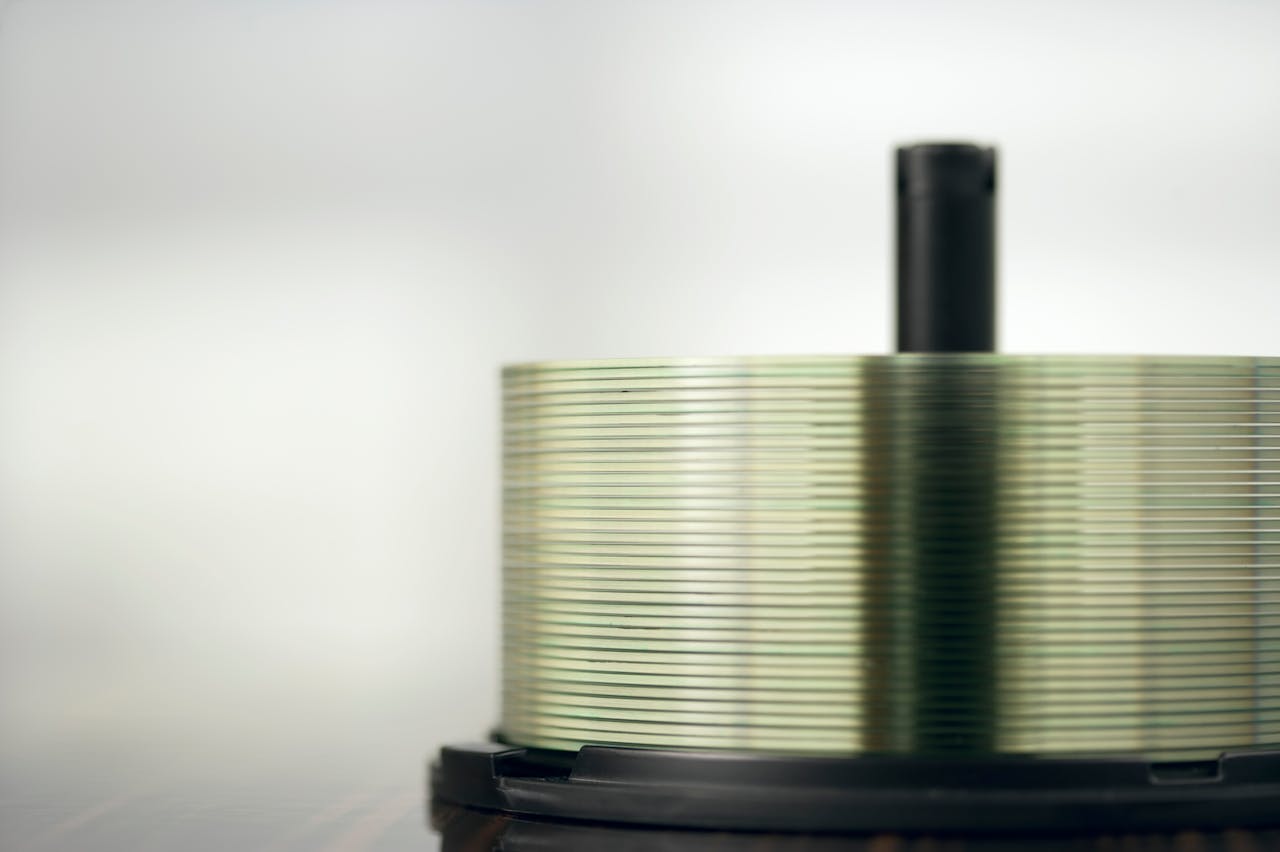 Detailed view of a stack of compact discs on a spindle, highlighting their reflective surfaces.